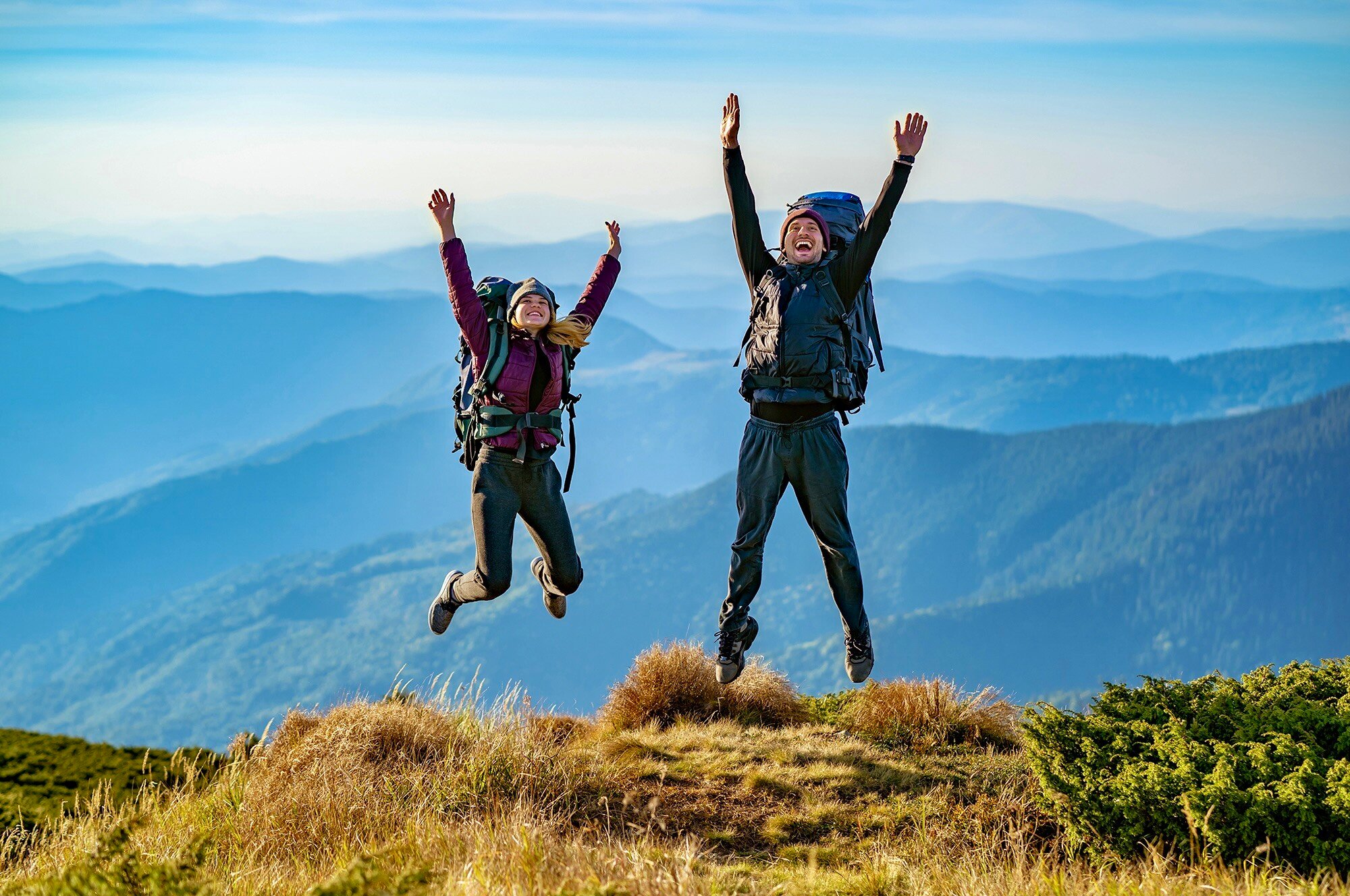 man-woman-with-backpacks-jumping-mountain (3)